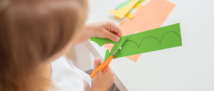 A Child Developing Fine Motor Skills by Cutting Paper