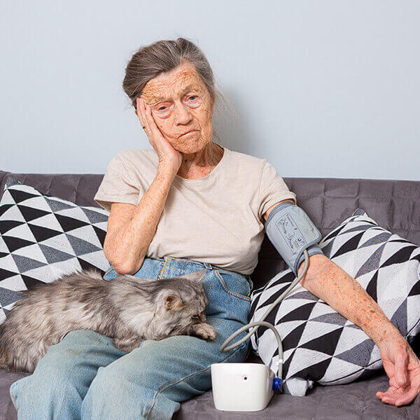 How Pets Benefit Disabled - Elderly lady taking her blood pressure with pet cat