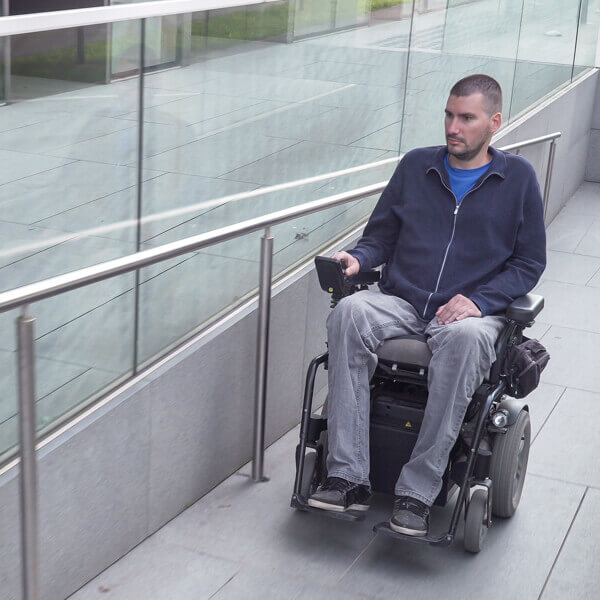 Man in Wheelchair Using the Wheelchair Access Ramp at Work
