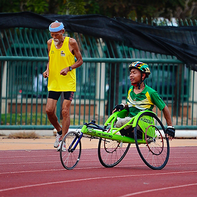 wheelchair-athelete-running-wheelchair-racing-on-paralympic-track-next-to-elderly-man Paralympic Athlete